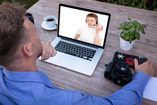 Man sits in front of a laptop and makes a video phone call